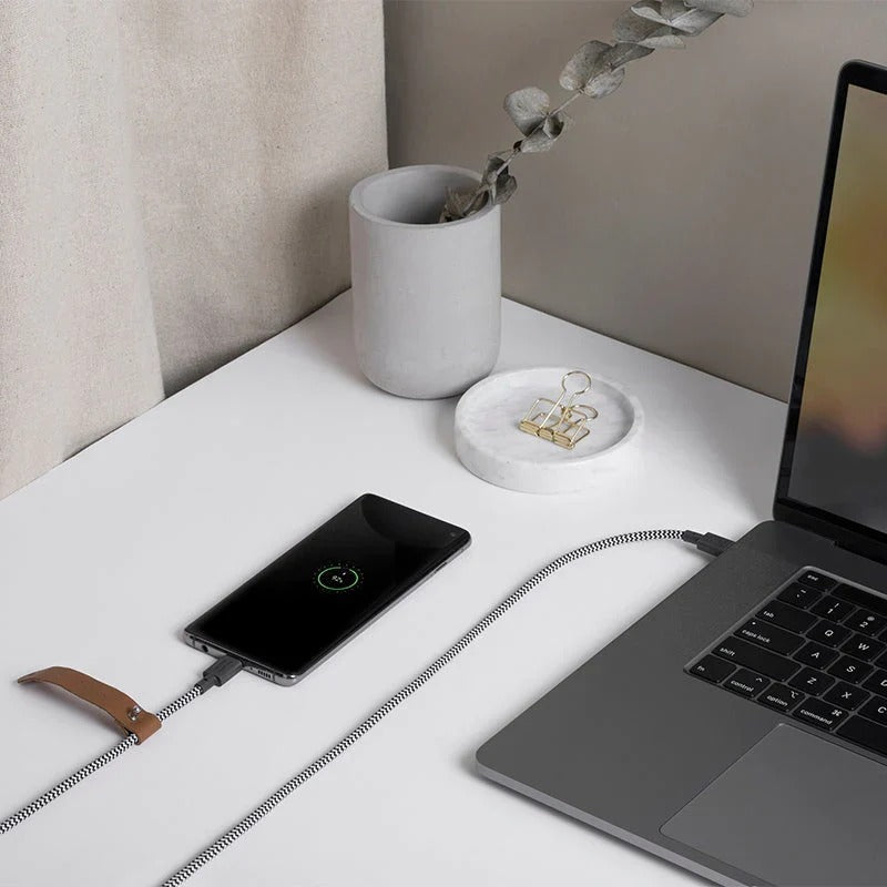 Native Union Belt-kabelen i zebramønster brukt til lading på et skrivebord med MacBook
